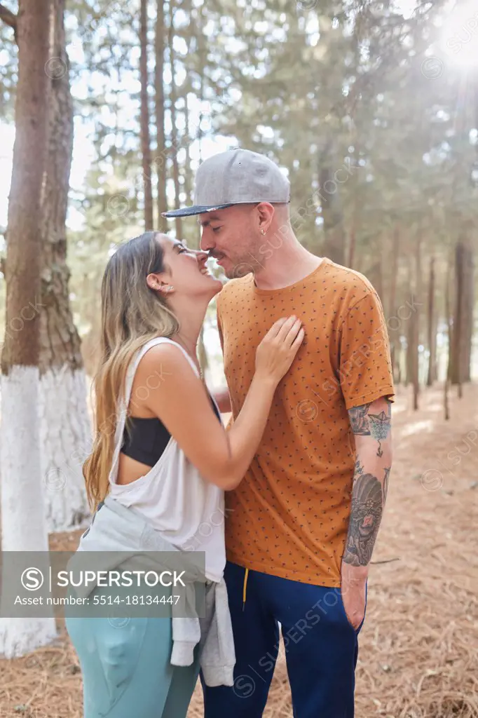 happy engaged couple kissing in the middle of the forest