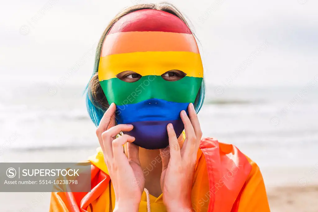 Masked person with authentic hand painted LGBT mask on the beach