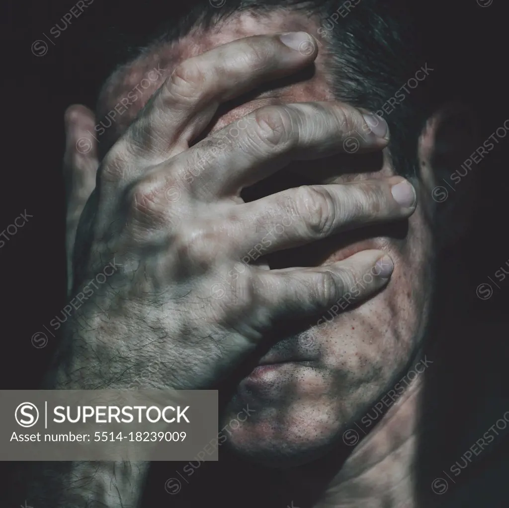 man covering his face with his hand