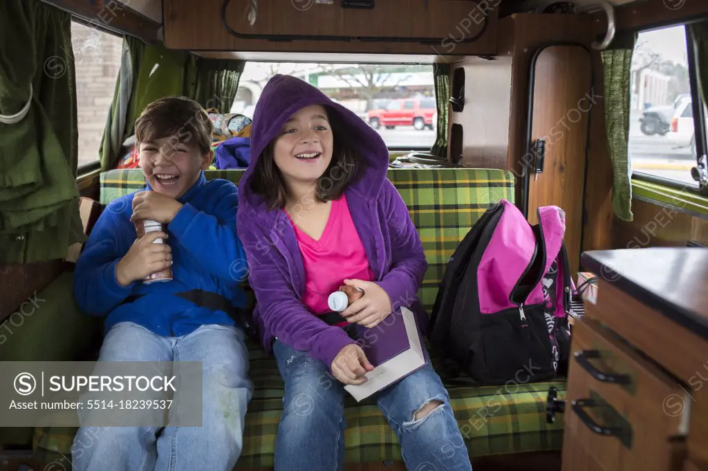 A brother and sister laugh in back of VW camper van during Idaho