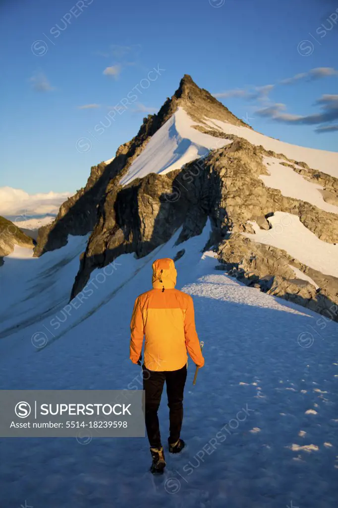 Rear view of climber approaching challenging mountain summit