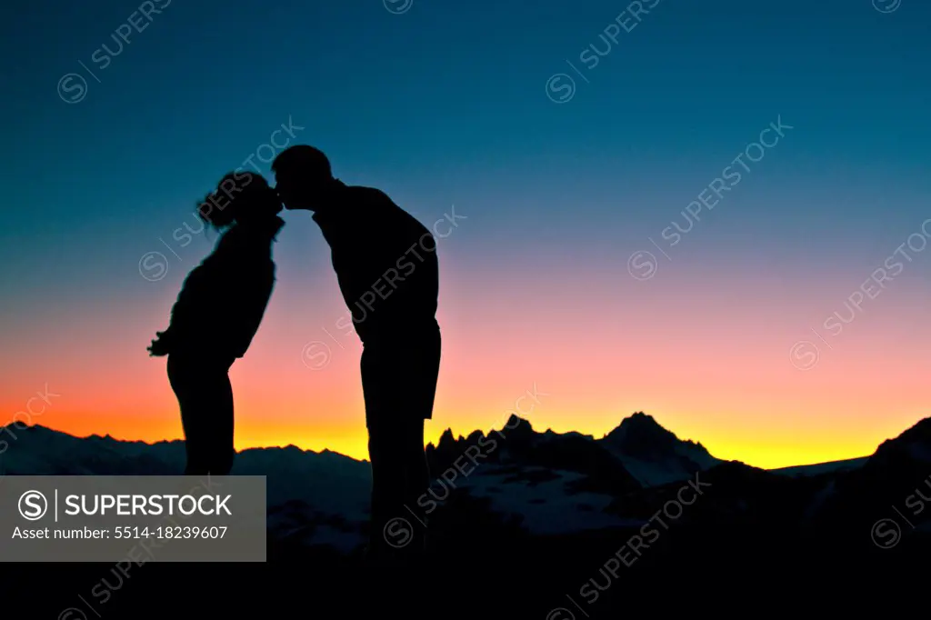 Silhouetted view of romantic couple kissing in the mountains at sunset