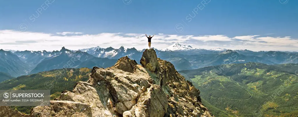 Hiker celebrates hiking to the summit of a rocky mountain, scenic view