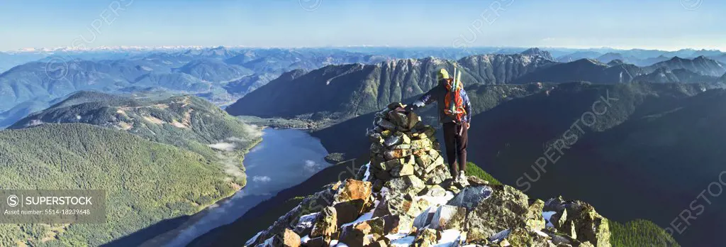 Rear view of backpacker standing on rocky mountain summit, scenic view