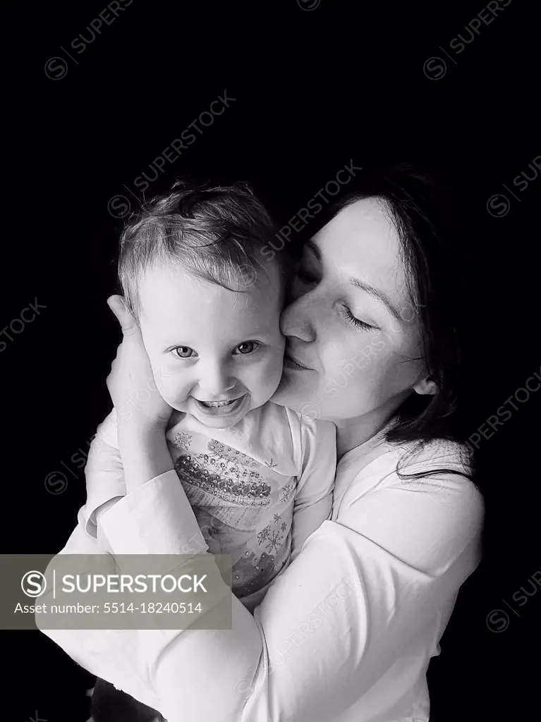black and white portrait of mother hugging and kissing smiling girl