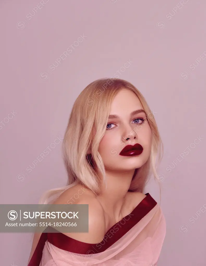 Beauty fashion model portrait with shiny blonde hairstyle with red lips on pink background