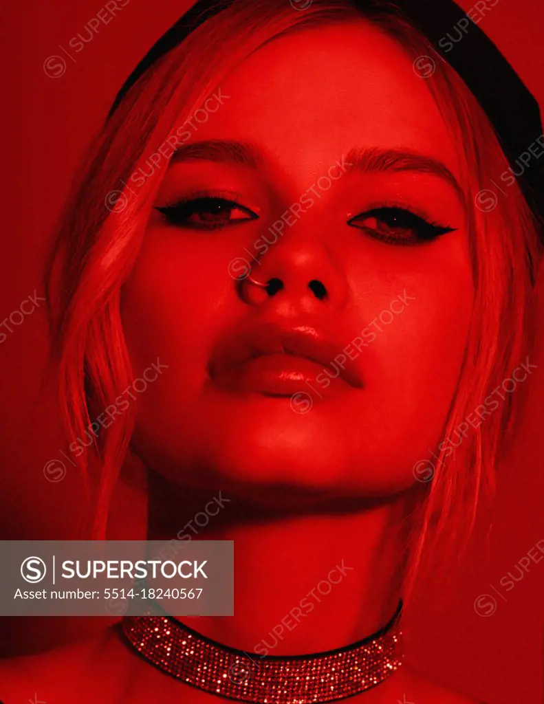 Beauty fashion portrait with red lighting filter. Beauty girl face close up. Closeup blonde woman with dark liner eyes and black hat. neon light red color. stylish fashion portrait art - imag