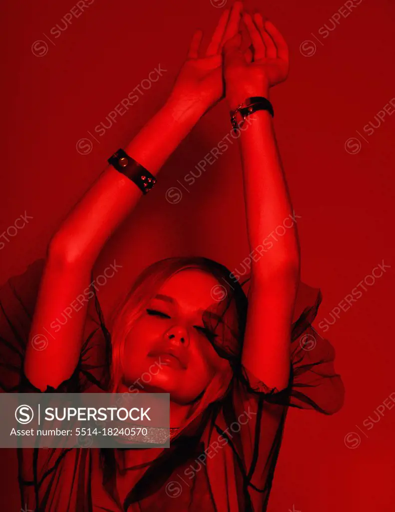 Beauty fashion portrait with red lighting filter. Beauty girl face close up. Closeup blonde woman with dark liner eyes and black hat having fun, good mood, dancing, relaxing. neon light red c