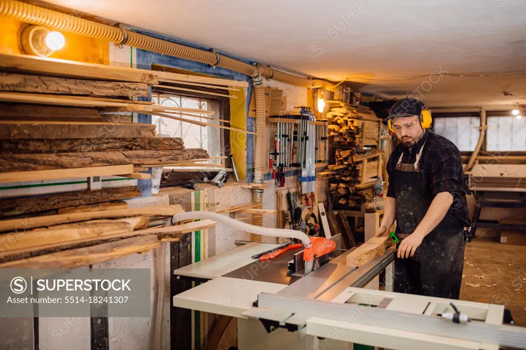 carpenter works with wood on machine in workshop