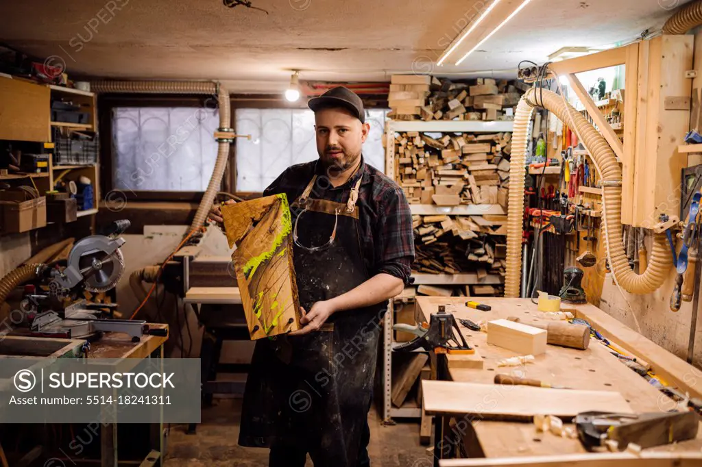 Portrait of carpenter with piece of wood in workshop