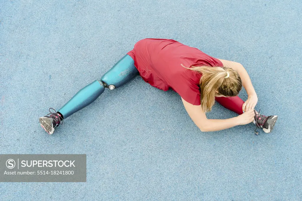 Flexible sportswoman with artificial leg training at stadium