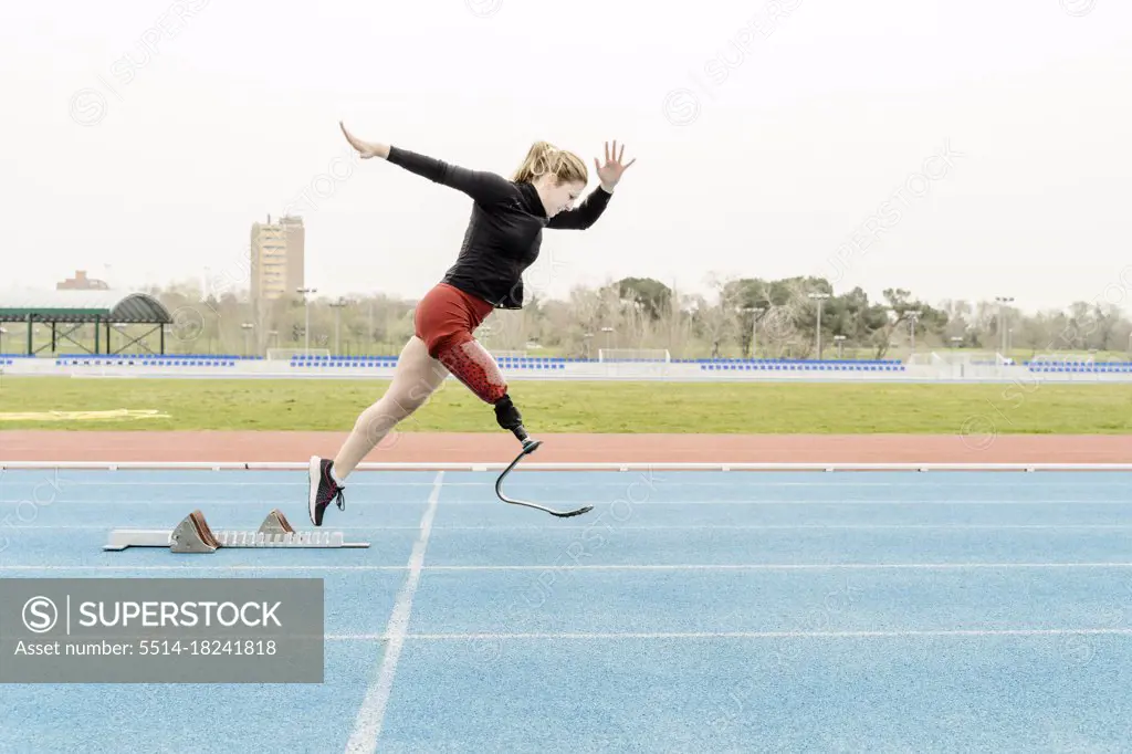 Sportswoman with prosthetic leg running near the starting blocks