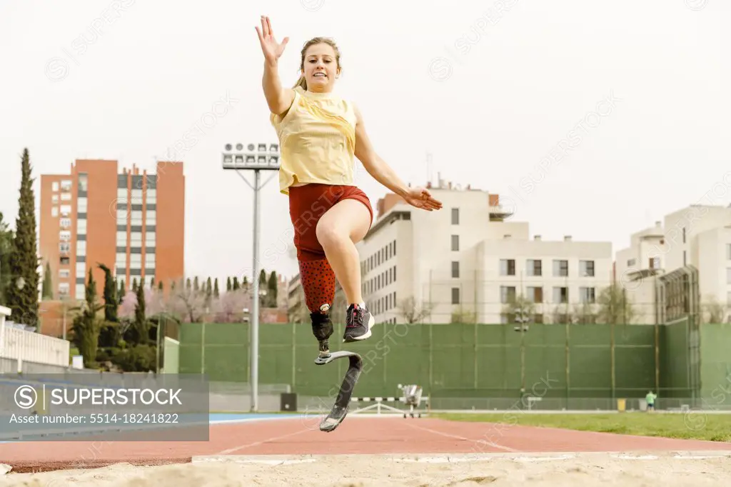 Female athlete with disability running towards sandpit