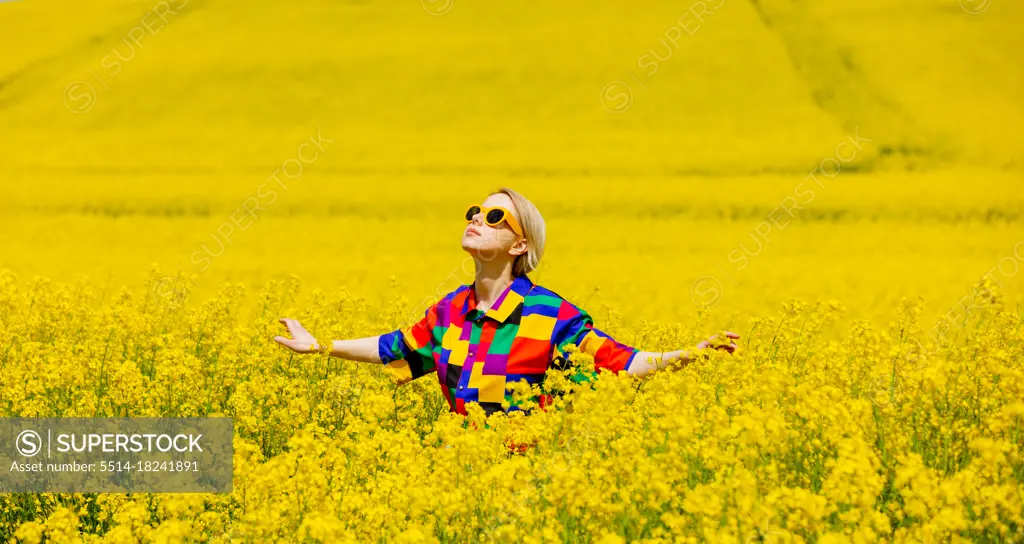 Beautiful female in 90s stylish shirt in rapeseed field