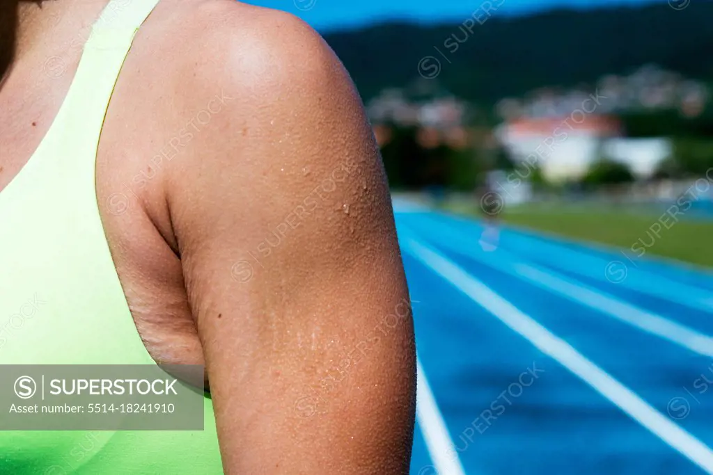 Crop sweaty woman in an athletics track