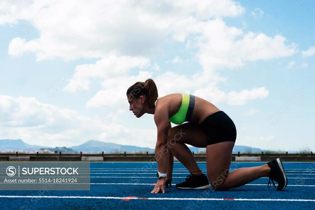 Woman athlete on running field in starting position