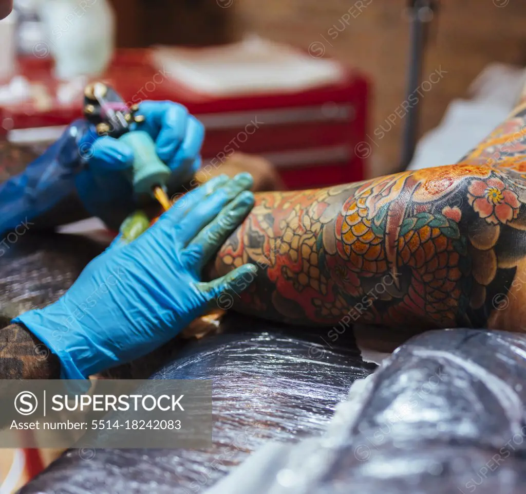 Detail of an artist's hands tattooing a japanese tattoo