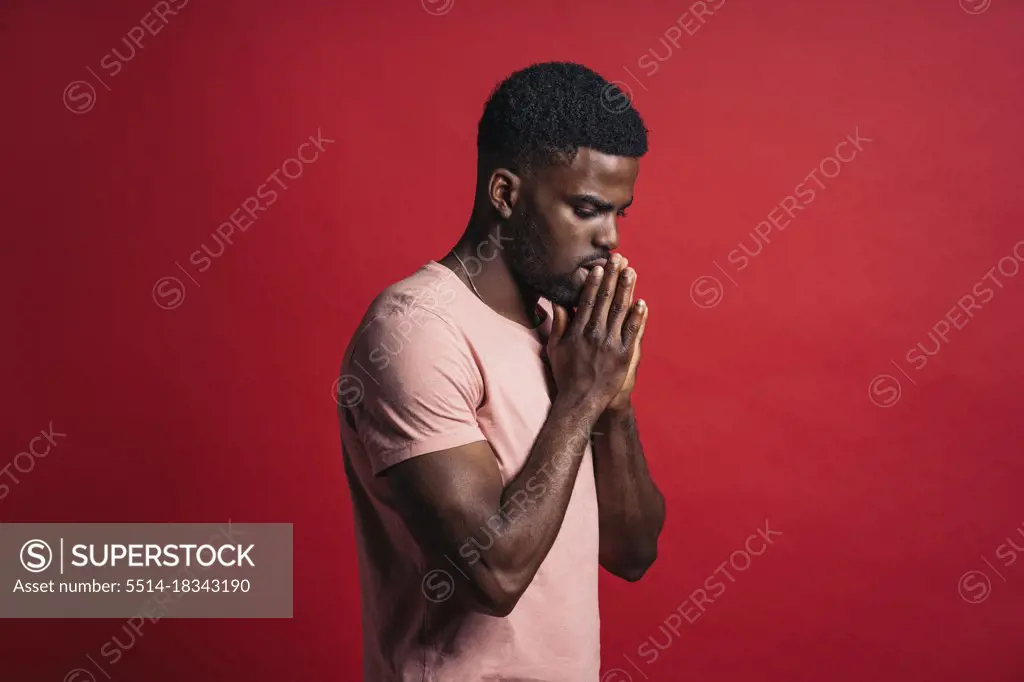 Portrait of an emotional black man in studio with hands in prayer