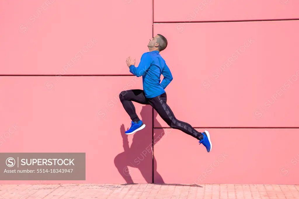 Sporty man exercising on fuchsia wall