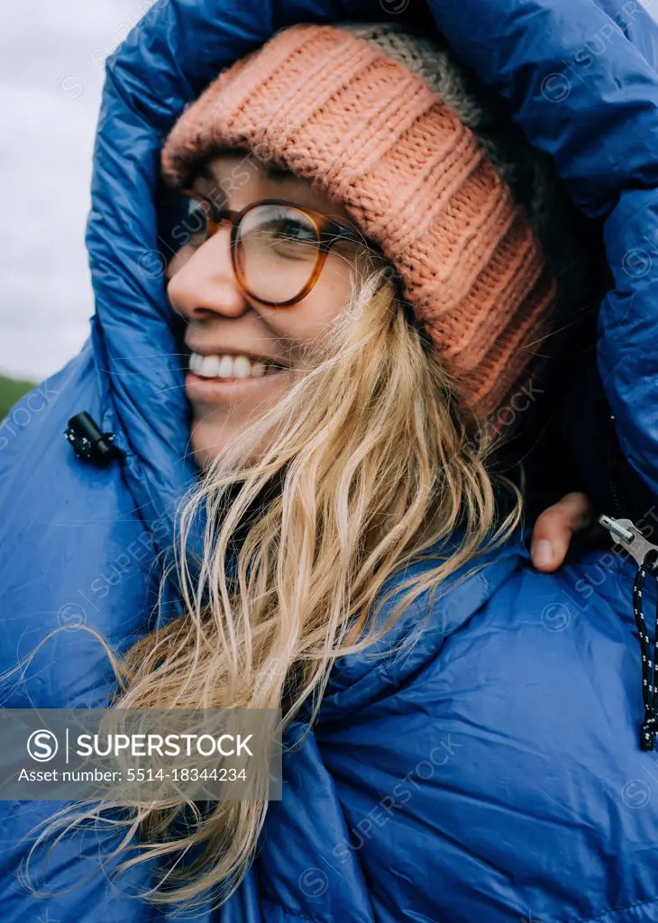 woman smiling in a sleeping bag whilst camping in the Jurassic coast