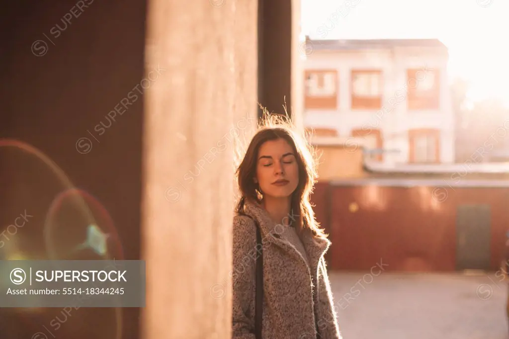 Portrait of young woman with eyes closed standing in city