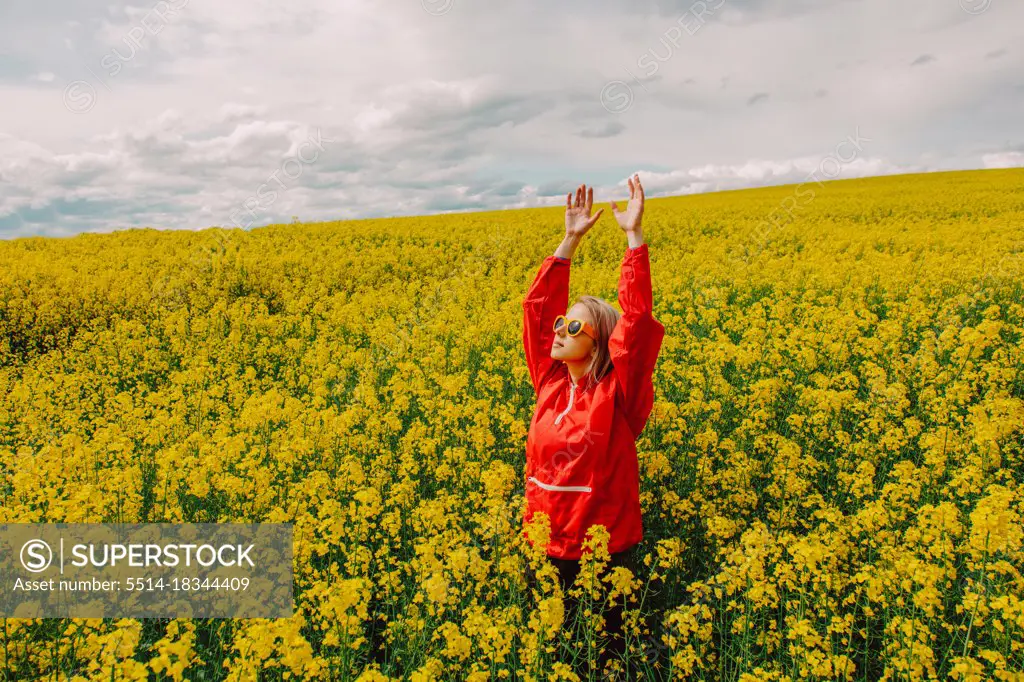 Blonde in sunglasses and red tracksuit in rapeseed field