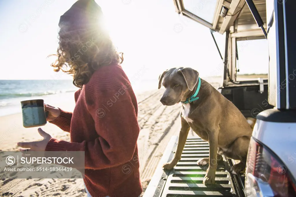 Woman and dog in the morning beach car camping