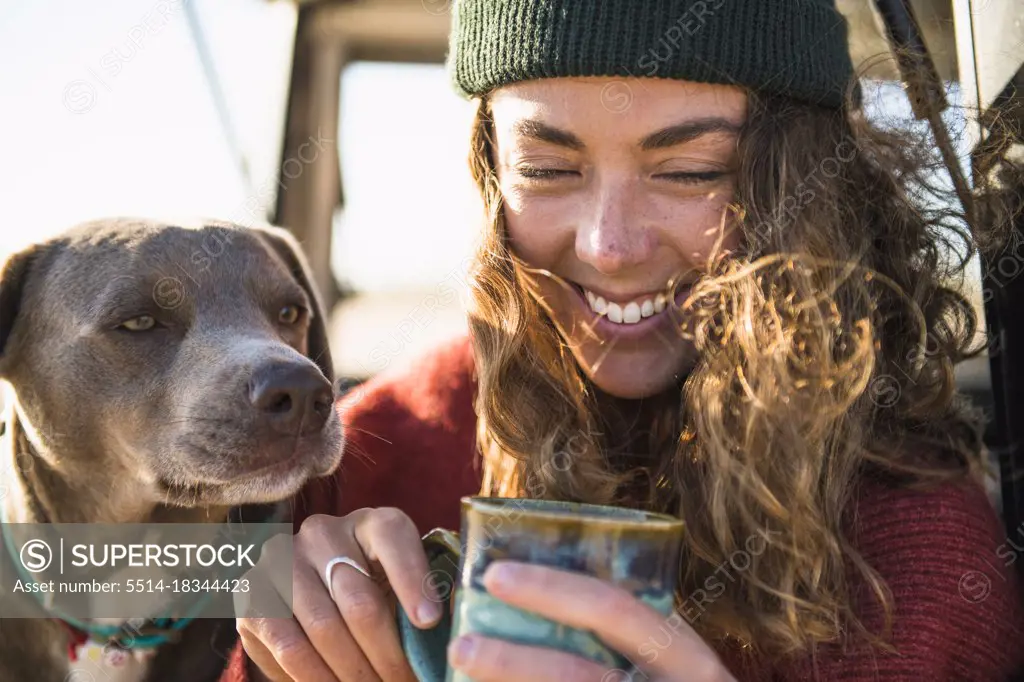 Young woman enjoying cup of coffee in the morning beach car camping