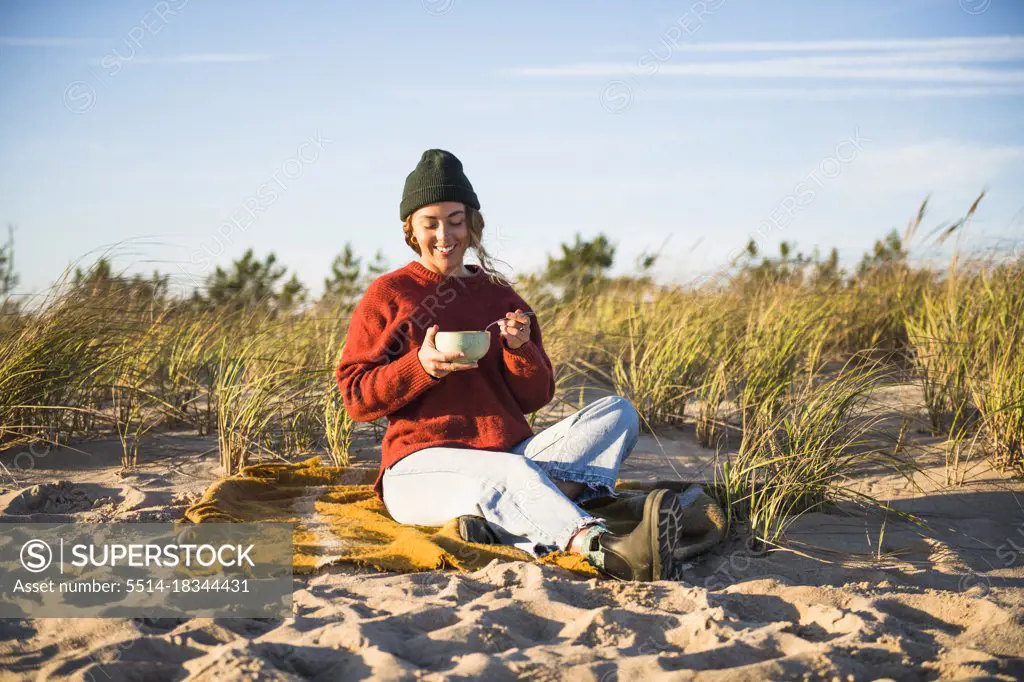 Young woman enjoying soup while beach car camping alone