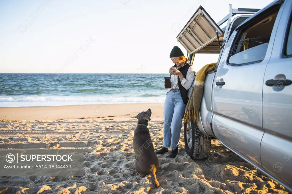 Young woman and her dog while beach car camping alone