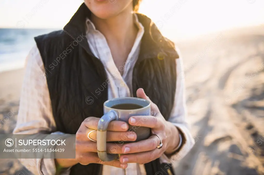 Young woman holding mug while beach car camping alone
