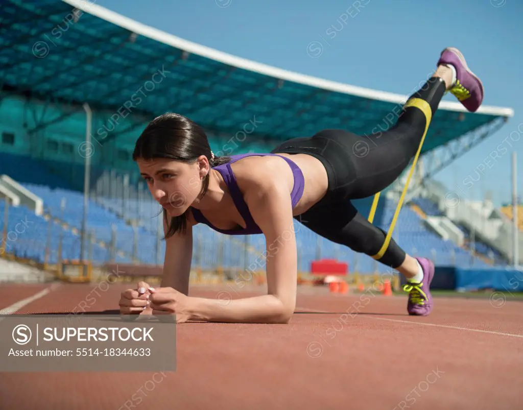 Sportswoman doing plank with resistance band