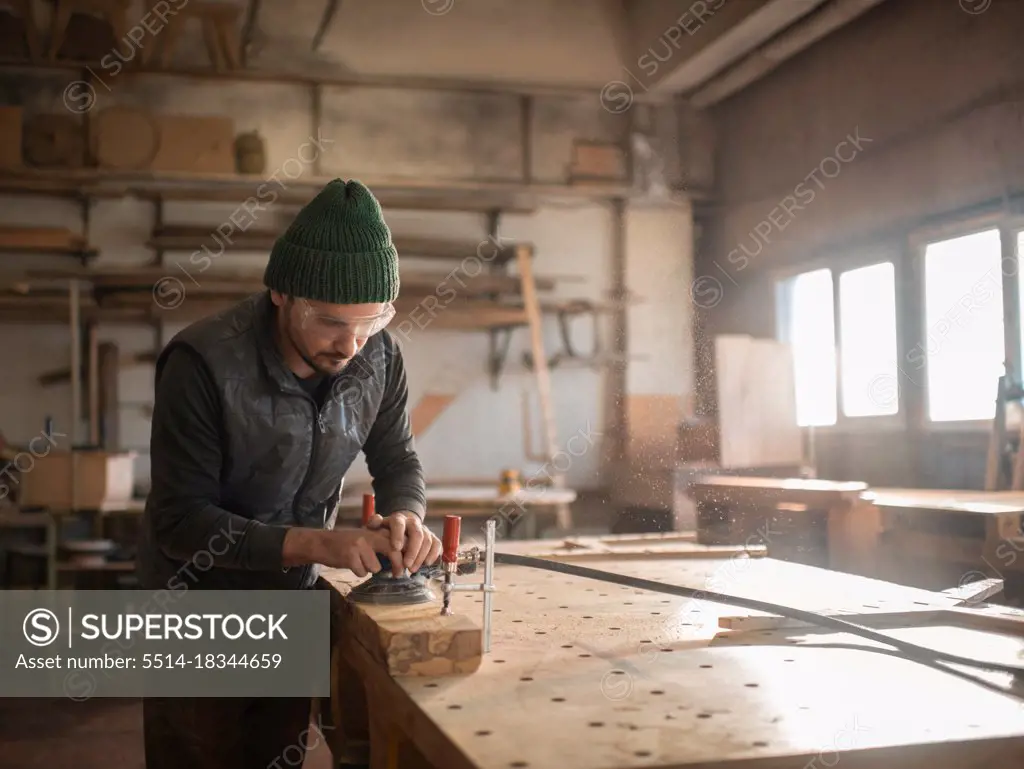 Male carpenter polishing wooden plank