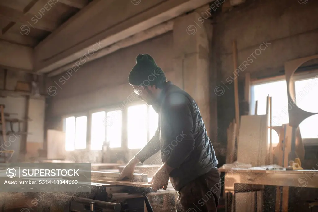 Male carpenter cutting wooden plank