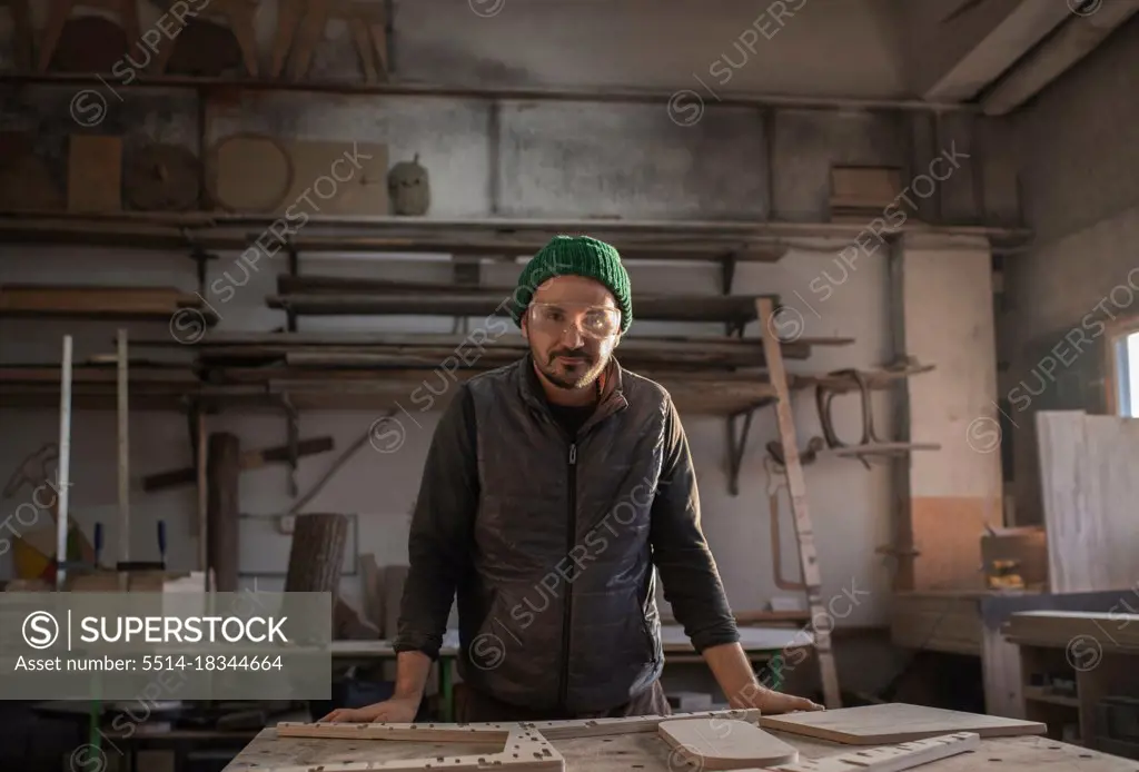 Male carpenter leaning on workbench