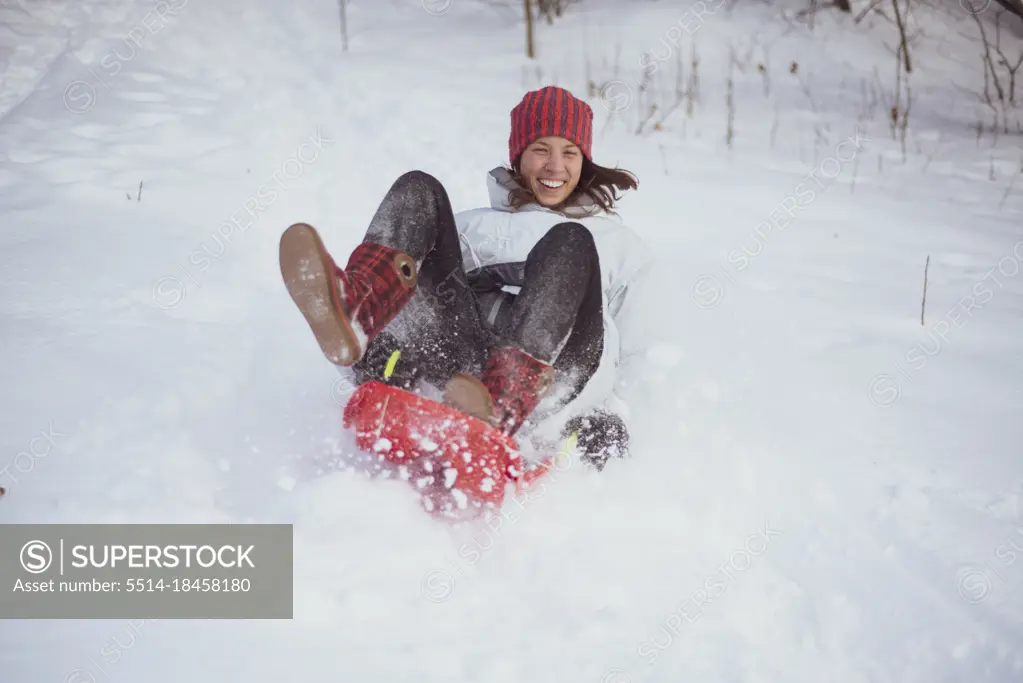 happy European woman laughs and sleds down snow hill in czech republic