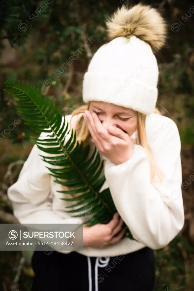 Teen Girl in Winter Hat Holding Green Fern While Laughing