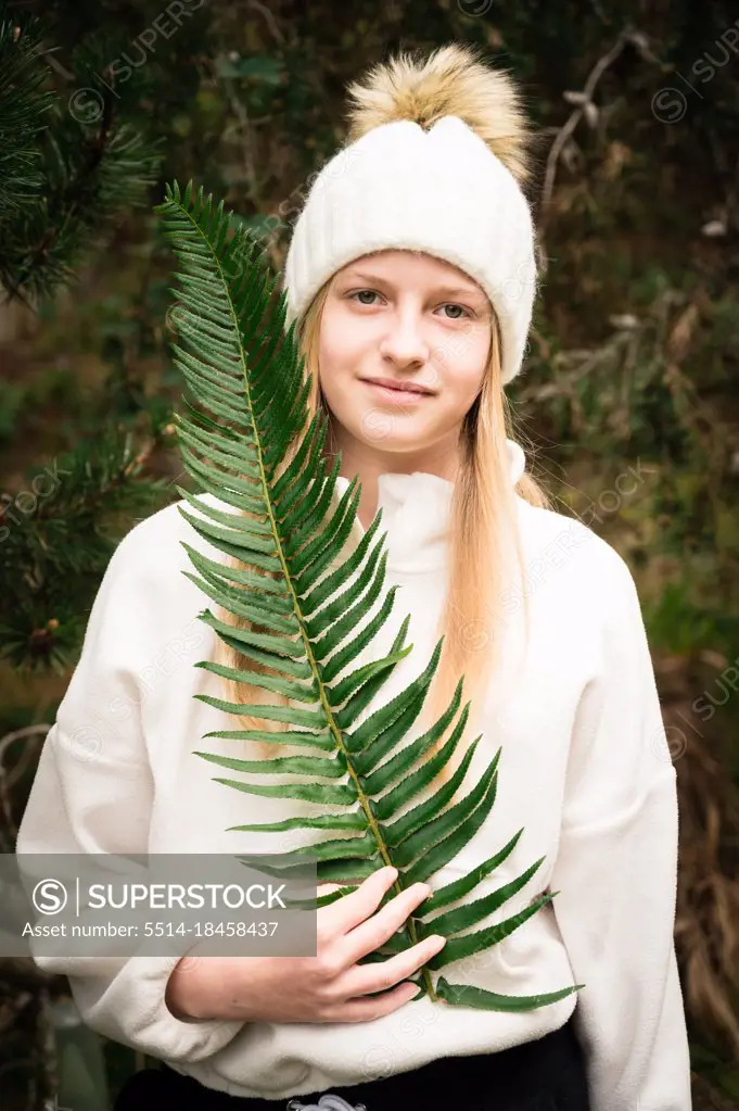 Young Girl In Woodland Setting Holding Large Fern Frond