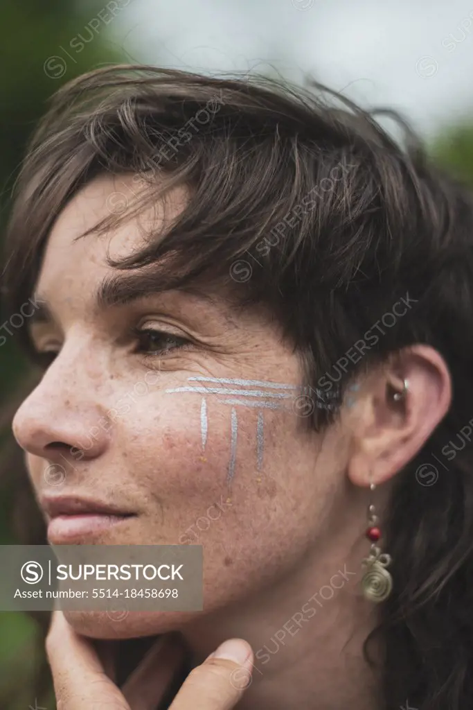 Beautiful woman with brown hair, freckles, silver tribal facepaint
