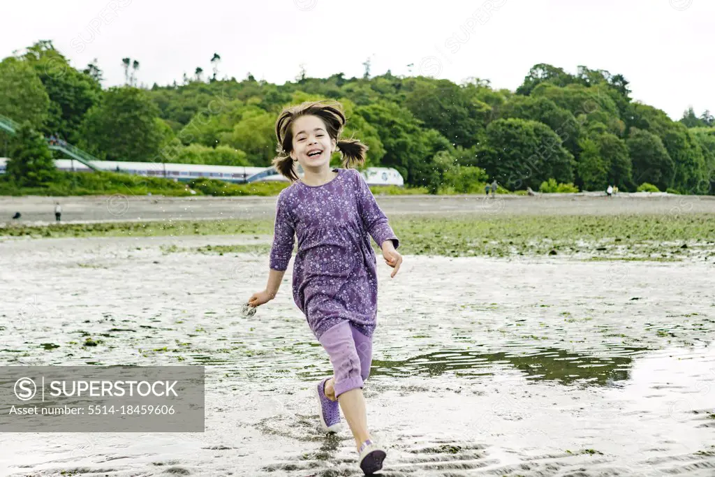 Front view of a young girl running across a Seattle beach