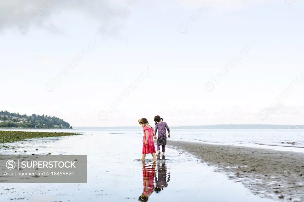 Wide view of two sisters exploring together on the beach
