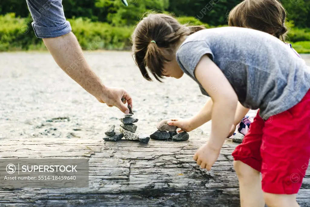 Closeup view of a family stacking rocks together on a beach