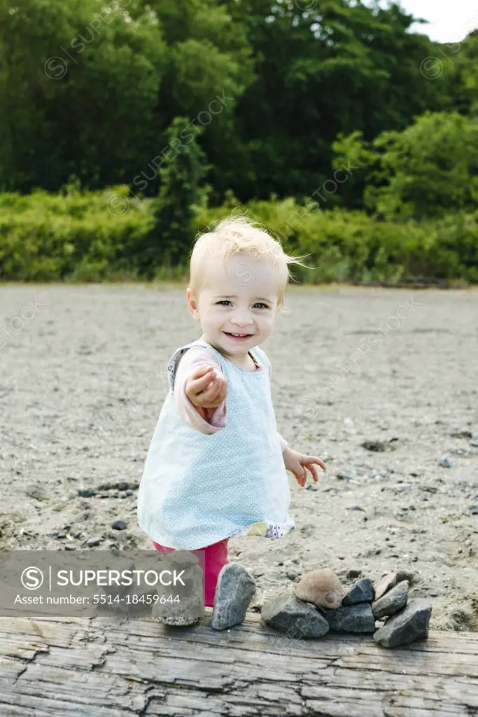 Closeup portrait of a young girl holding out a rock on the beach