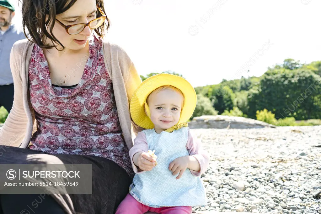 Closeup view of a young girl sitting on a beach with her mother