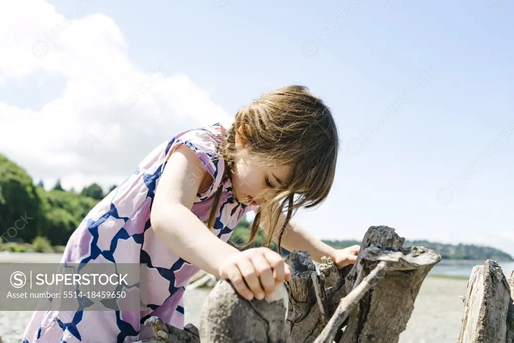 Closeup view of a young girl climbing on driftwood at Carkeek Park