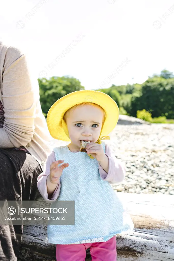 Closeup portrait of a young girl eating a sandwich on the beach