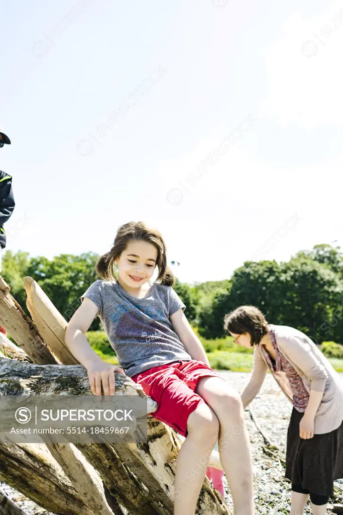 Closeup portrait of a young girl sitting on driftwood at a beach