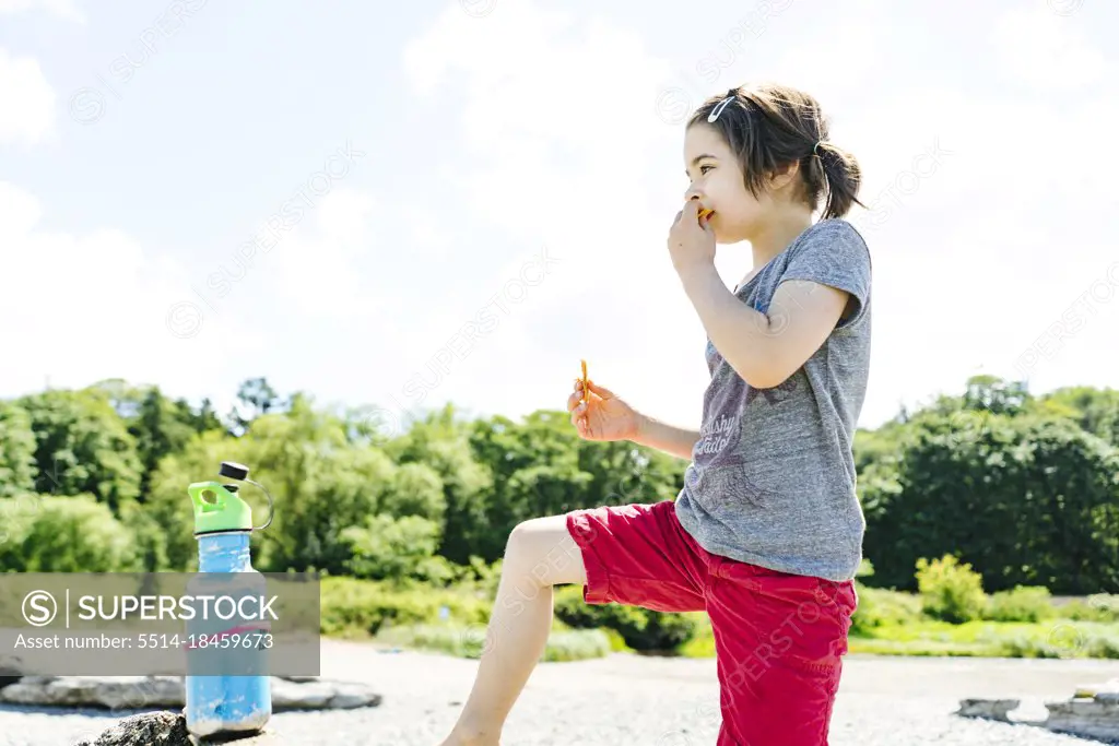Side view of a child eating a snack on the beach