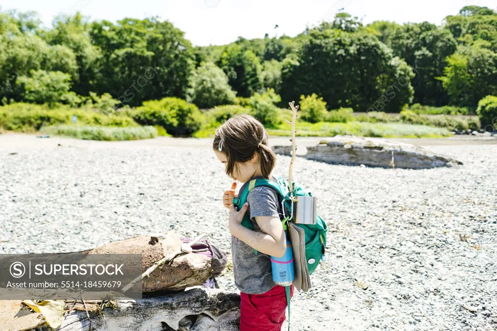 Side view of a young child with an adventure backpack on the beach