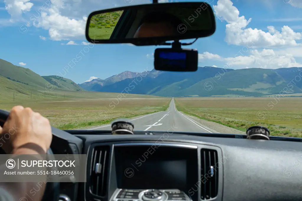 Man driving car on country road in Altay mountains. View from car.